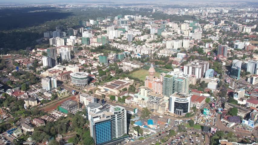 A beautiful aerial drone footage of the city of Nairobi, Kenya, showcasing the bustling urban office spaces, modern residential areas, the Nairobi Expressway, and Waiyaki Way. Captured during the day.