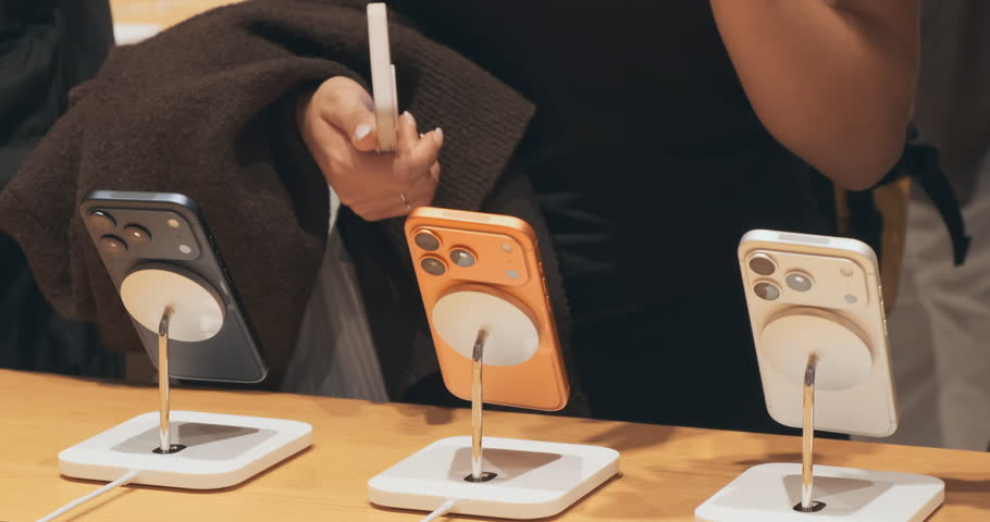 New smartphones lineup at mobile retail store on shoppers background, close up. Modern phone technology. Woman consumer purchase device in gadget shop. Choosing of new mobile phone. Consumer Culture