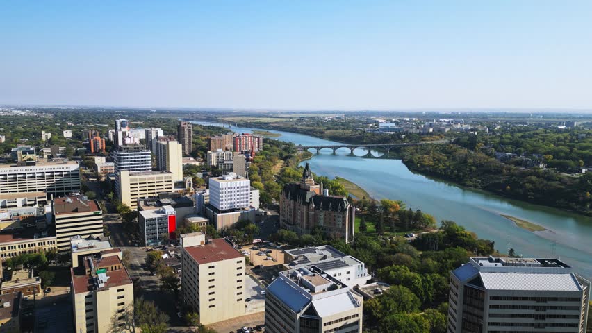 Drone shot shows Saskatoon bridge spanning river into downtown core, fall day
