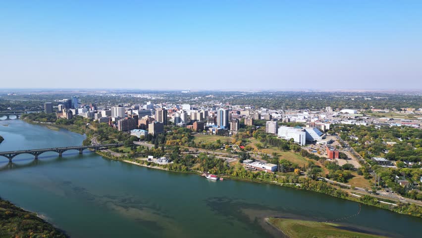 Slow forward aerial focusing on Saskatoon downtown, river and bridges in fall
