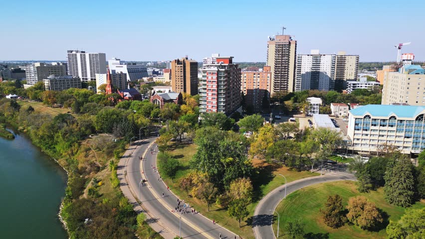 Drone view shows marathon runners by Saskatoon riverfront under clear blue sky