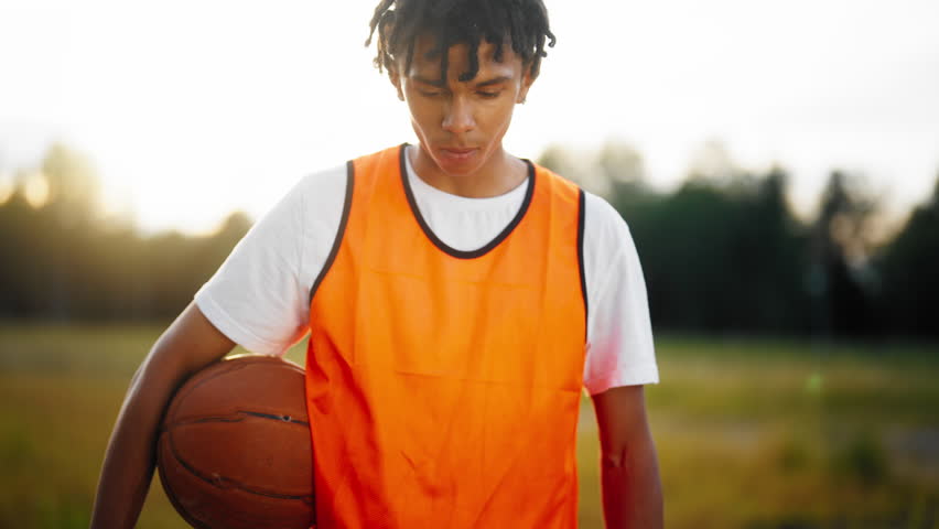 Portrait of tired sportsman after workout outdoors, young basketballer in nature . Sportswear and professional ball, motivated sportsman training hard for win and become champion, medium shot outside