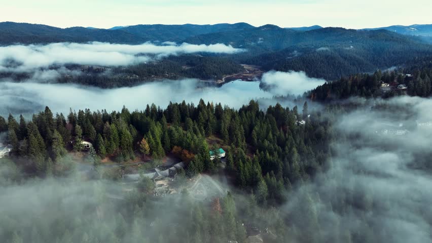 Aerial drone view above the clouds with forest hills, rivers, and houses in Washington State USA
