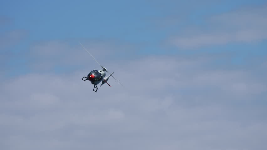 Military helicopter performing aerial maneuver against clear blue sky during air show