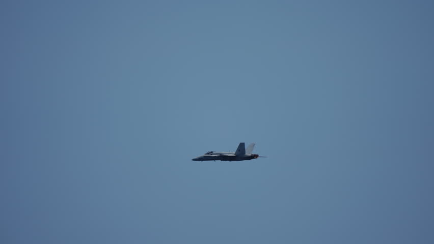 Solo fighter jet flying at steady altitude under clear blue sky with engines in afterburner