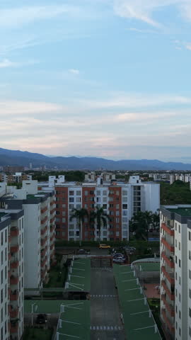 Aerial shot showcasing Valle del Lili's residential buildings with a backdrop of mountains under a pastel sky dynamic movement captivating scenes cinematic quality