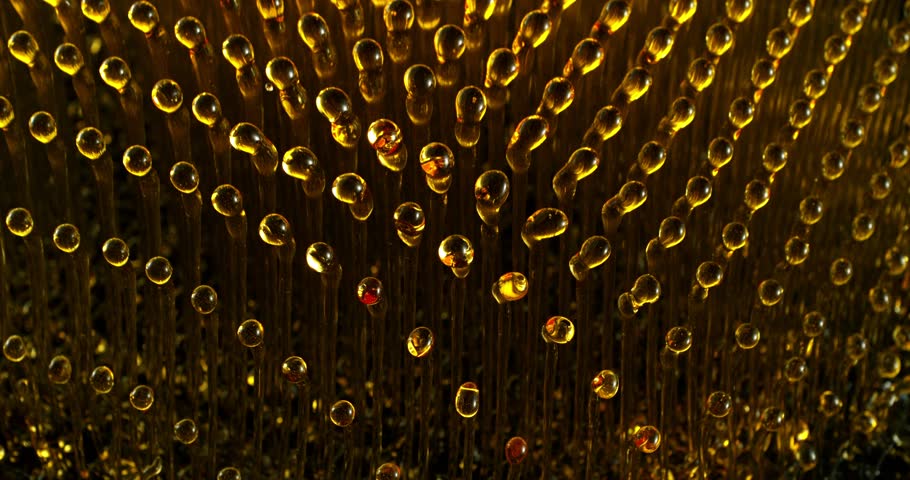 Super Slow Motion of Splashing Oil Drops on Black Background. Filmed on High Speed Cinema Camera, 1000fps. Abstract Golden Oil Splashes, Fuel, Beauty or Cooking Concept.