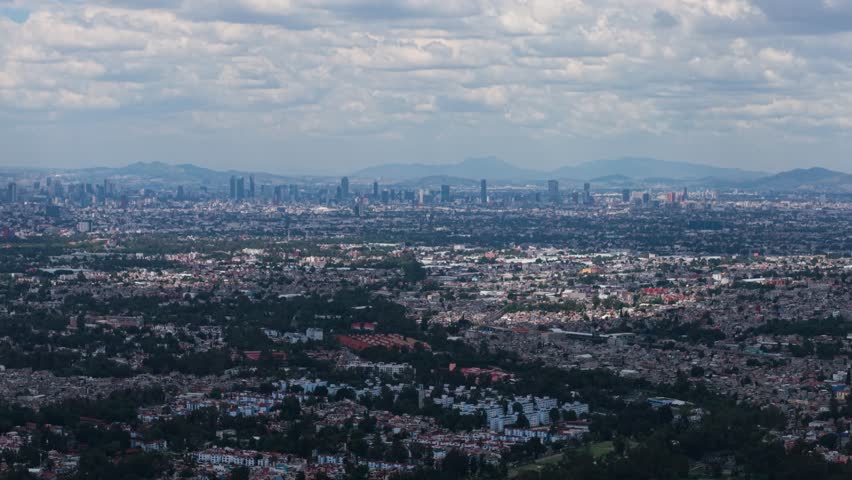 Drone shot of Mexico City skyline from afar, showing vast urban area