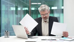 Confused puzzled mature businessman having difficulty with paperwork sitting at workplace in business office. Frustrated financier unhappy with bad financial results holding and reviewing documents - Powered by Shutterstock - Get 15% off with code: PIKWIZARD15