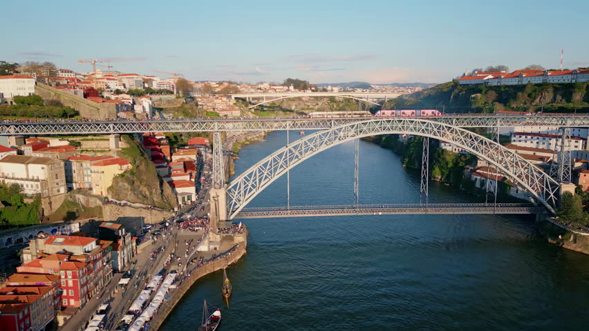 Dom Luis bridge across Douro river aerial view. Beautiful landmark architecture at urban skyline. Monumental steel arch raising over calm water connecting Porto and Vila-Nova-de-Gaia in Portugal.
