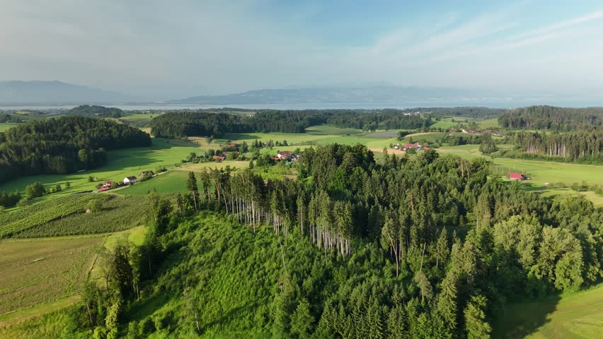 Aerial view of rural German countryside near Lake Constance with green fields, forests and traditional village at sunset