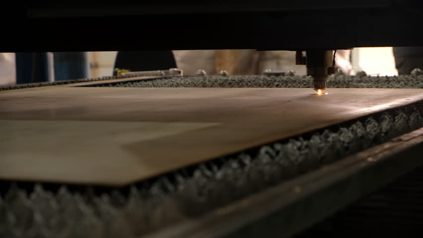 Industrial laser cutting machine operating on metal sheets creates title. Plasma cutting in metal industry. Laser engraving marking shape in metalworking on plant factory. Manufacturing metal parts.