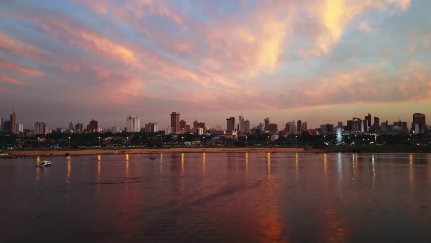 Beautiful sunset reflections into Paraguay river bay, ascending view reveals Asuncion capital city cityscape