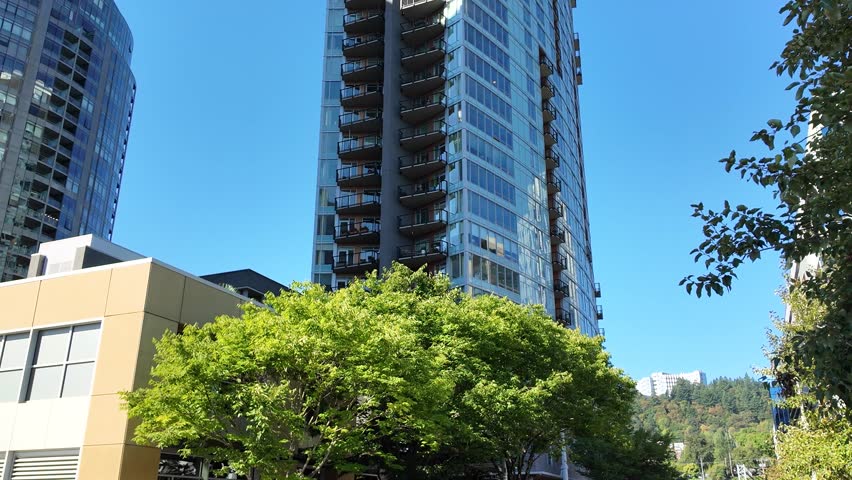 4K smooth stabilized video of modern high rise buildings in South Waterfront district of Downtown Portland Oregon, showing contemporary glass architecture and urban city environment under blue sky