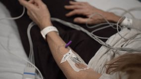 A mature woman is lying in a hospital bed connected to heart monitors and EKG equipment, receiving medical attention in an emergency room. - Powered by Shutterstock - Get 15% off with code: PIKWIZARD15