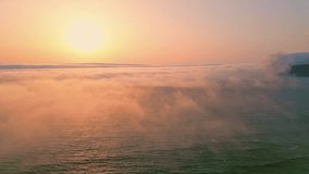 Amazing ocean sunset illuminating white fog covering calm water aerial view. Golden sun disc setting over sea horizon with soft evening mist. Picturesque summer evening drone shot. Waves rippling - Powered by Shutterstock - Get 15% off with code: PIKWIZARD15