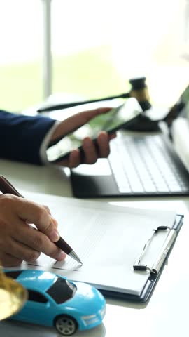 A judge holding a gavel hitting a toy car in a contract document represents automotive law, insurance disputes, car ownership, and legal decisions.