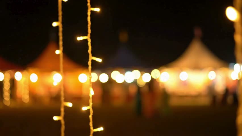 Golden string lights hang over a Garba ground, creating a warm, festive atmosphere for a cultural celebration.
