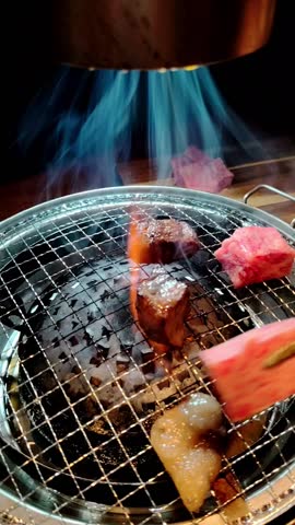 BBQ wagyu beef cubes on charcoal grill with fire flame smoke, Japanese style yakiniku BBQ barbecue grill at restaurant