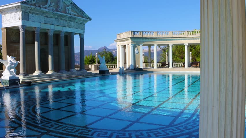 Establishing reveal of ornate decorative pool with columns and blue water at castle grounds, California
