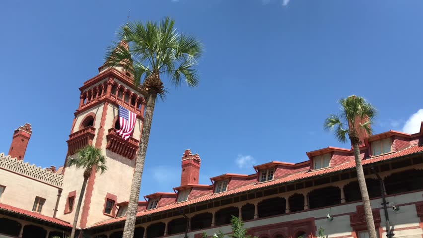 Flagler College, a historic landmark and popular tourist attraction in St. Augustine, Florida, showcases its Spanish colonial architecture and vibrant red roof tiles under a clear blue sky