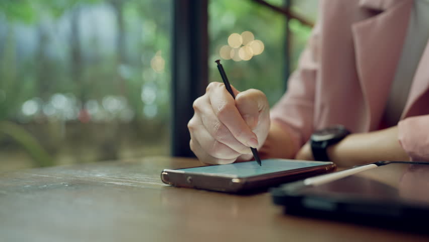 Asian professional woman multitasking with smartwatch and stylus on tablet, concept of digital career and time management - Powered by Shutterstock - Get 15% off with code: PIKWIZARD15