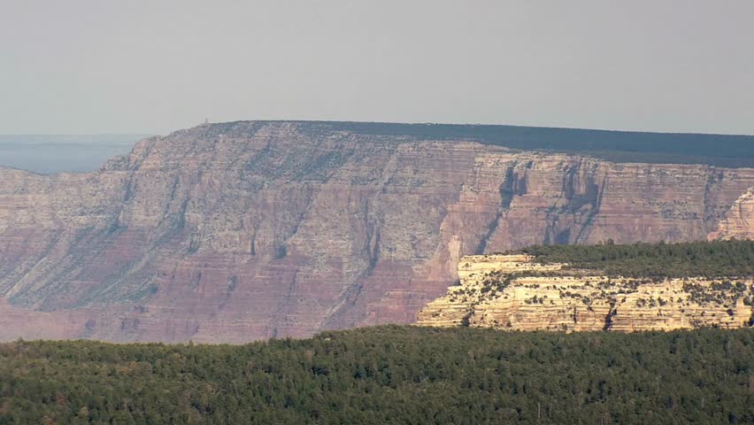 Grand canyon landscape with layered rock formations and green forest below