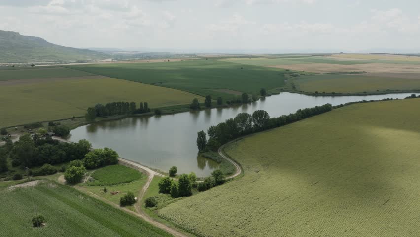 Aerial view of a landscape with a pond surrounded by agricultural fields.