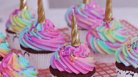 Chocolate cupcakes decorated with colorful unicorn frosting and golden horn candles, showcasing whimsical dessert, festive celebration, and sweet indulgence. Perfect for food, holidays, lifestyle - Powered by Shutterstock - Get 15% off with code: PIKWIZARD15