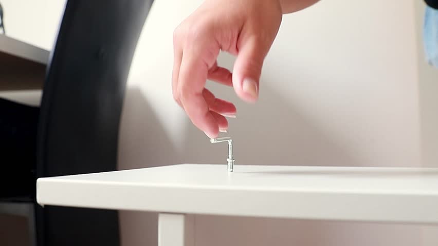 Womans hand using Allen key for furniture. Close up of hand tightening bolt.