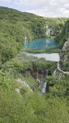 Aerial view of Plitvice Lakes waterfalls in Croatia on a beautiful sunny day, with turquoise water and sunlight breaking through the clouds.