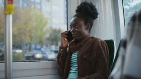 African American woman sitting on bus laughing during phone conversation. Passenger holding smartphone close to ear enjoying remote communication. Modern technology connecting people while commuting. - Powered by Shutterstock - Get 15% off with code: PIKWIZARD15