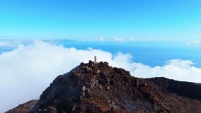 Hiker Man on Top of Mount Pico above Clouds on Sunny Day. Summit and Atlantic Ocean. Pico Island, Azores. Portugal. Aerial View. Orbiting - Powered by Shutterstock - Get 15% off with code: PIKWIZARD15