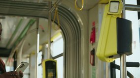 Charming African American woman holding smartphone close to yellow validator paying for ride on bus. Passenger in striped shirt and jacket completing contactless payment. Modern technology. - Powered by Shutterstock - Get 15% off with code: PIKWIZARD15