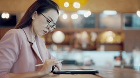 Asian businesswoman working on digital tablet with data chart overlay in modern cafe, symbolizing smart workspace, productivity, technology, and real-time data visualization for business analysis. - Powered by Shutterstock - Get 15% off with code: PIKWIZARD15