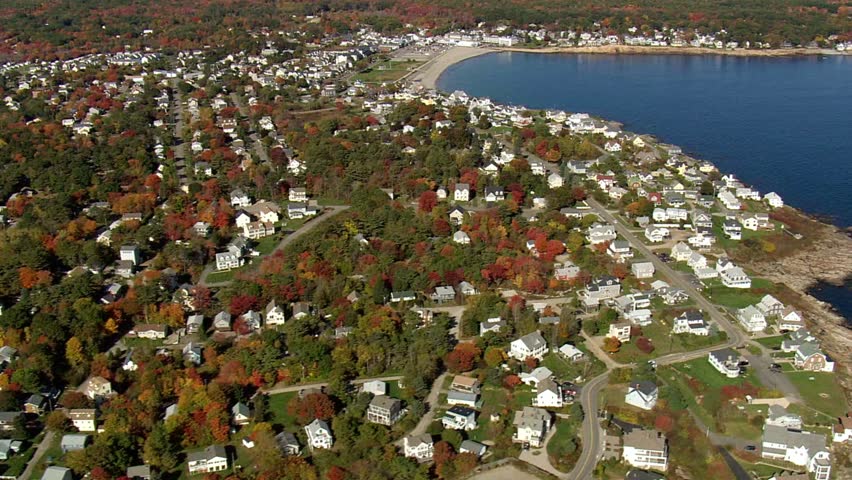 Aerial view of a coastal town with colorful fall foliage near the ocean