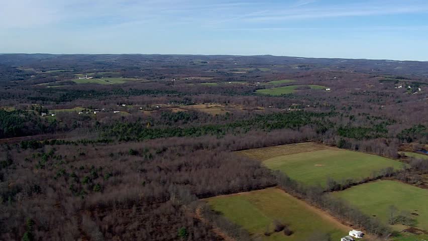 Aerial view of a vast landscape with fields and dense forests under a blue sky