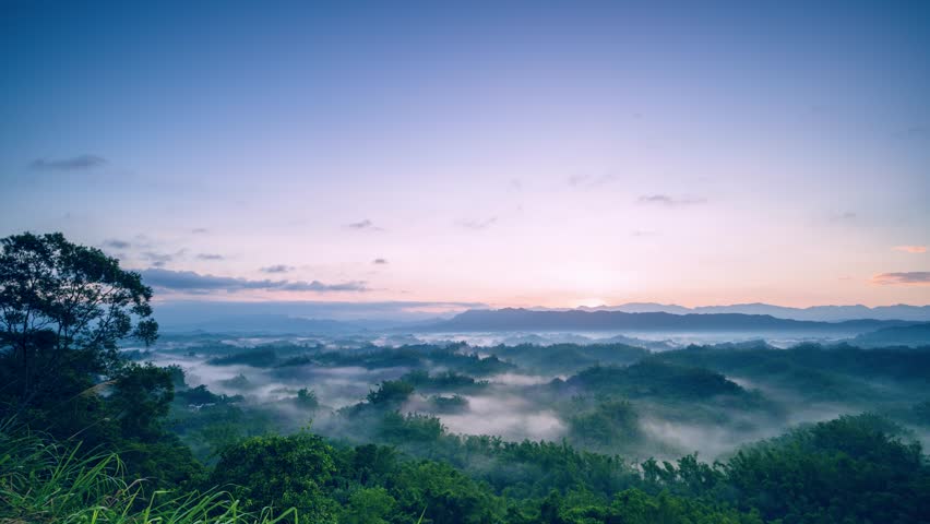 Time lapse of the spectacular autumn sunrise over the misty hills of Er-Liao in Zhuo-Zhen Tainan Taiwan Sun rays pierce the morning fog creating beautiful light.