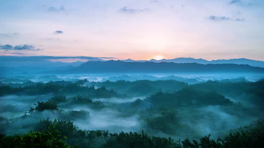 Time lapse of the spectacular autumn sunrise over the misty hills of Er-Liao in Zhuo-Zhen Tainan Taiwan Sun rays pierce the morning fog creating beautiful light.