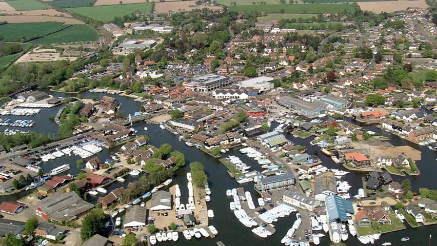 Aerial view of a charming town nestled along a river with numerous boats