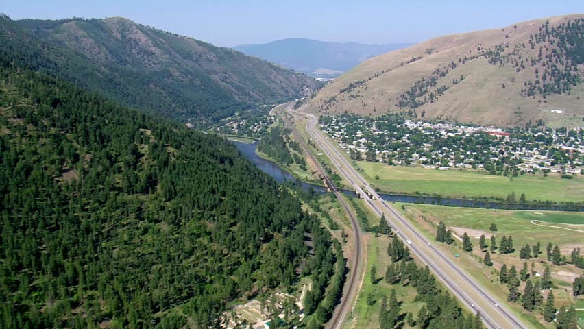 Aerial view of a highway and river running through a valley near a town
