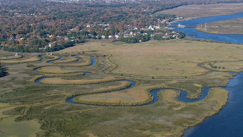 An aerial view shows a winding river flowing through a marshland landscape