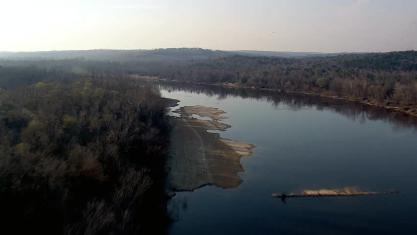 Aerial view of a river winding through a forest on a hazy day