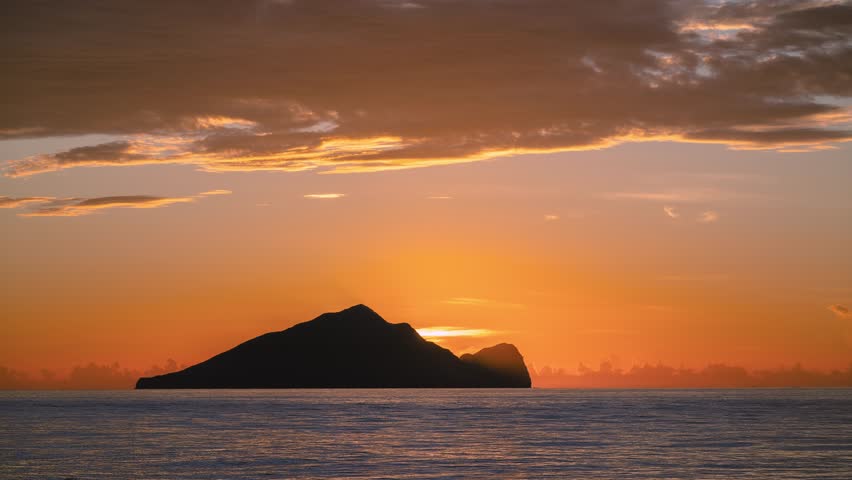 Time lapse of the sun slowly rising from behind Guishan Island in the Pacific Ocean near Zhuangwei Yilan Taiwan The golden light creates a dreamy and spectacular seascape at dawn