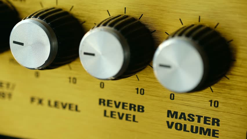 Close up musician hand adjusting reverb level and master volume knobs on vintage wooden guitar amplifier, fine tuning sound for music session in studio. Hand adjusting reverb volume knobs on amplifier