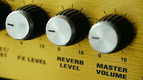Close up musician hand adjusting reverb level and master volume knobs on vintage wooden guitar amplifier, fine tuning sound for music session in studio. Hand adjusting reverb volume knobs on amplifier - Powered by Shutterstock - Get 15% off with code: PIKWIZARD15