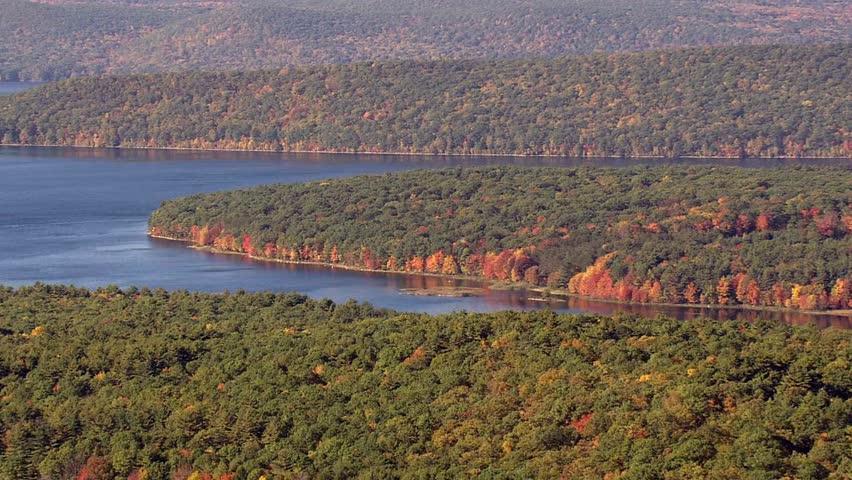 Aerial view of a lake surrounded by colorful autumn trees and forests