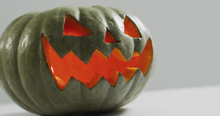 Magenta cyan ribbons drifting around green jack-o-lantern causing specks cascading forming veil. Festive, glow, mystical, halloween, celebration, decorative, vibrant