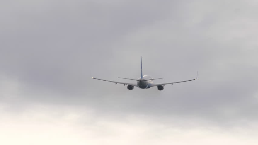 Back view of a commercial airliner climbing into the cloudy sky after takeoff. Symbolic image of aviation, travel, and freedom