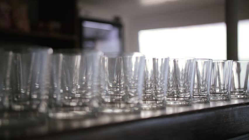 Row of clean glass cups on dark counter in sunlight